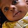 Jeremiah is registered to the contest to win money with this photo: baby, infant, face, closeup, yellow_clothing, curly_hair, eyes, skin, portrait, child, cute, expression, young, person, indoors, head, small_person, happy, apparel, newborn