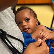 Jeremiah joined the competition — help win amazing prizes! baby, child, infant, blue_blanket, holding_hands, close_up, indoor, person, face, curious, soft_texture, gray_hoodie, skin, portrait, young_child, tender_moment, caring, expression, comfort, warmth