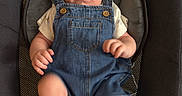 Noah joined the competition — help win amazing prizes! baby, denim_overalls, infant, baby_seat, socks, cute, child, padded_seat, indoor, person, young_child, blue_clothing, casual_wear, infant_clothing, seat, baby_boy, legs, hands, face, curious