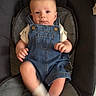 baby, denim_overalls, infant, baby_seat, socks, cute, child, padded_seat, indoor, person, young_child, blue_clothing, casual_wear, infant_clothing, seat, baby_boy, legs, hands, face, curious