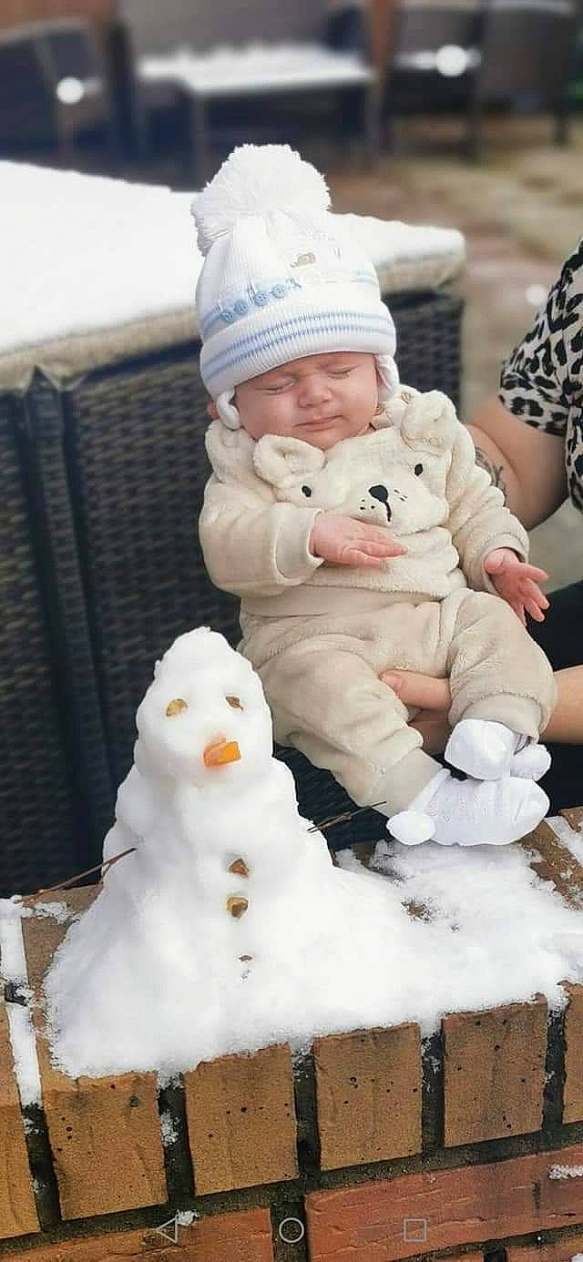 Travis joined the competition — help win amazing prizes! baby, baby_toddler_clothing, cap, cheek, child, face, freezing, fun, fur, happy, hat, head, headwear, knit_cap, person, photograph, sitting, snow, snowman, toddler