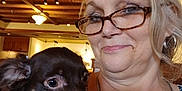 Ellamay is registered to the contest to win money with this photo: brown_dog, casual_clothing, chain_necklace, closeup, collar, dog, earrings, friendly, glasses, happy, holding_pet, indoor, light_fixture, pet, portrait, short_hair, smile, white_fur, woman, wooden_ceiling
