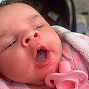 Delilah is registered to the contest to win money with this photo: baby, close_up, infant, pink_clothing, pacifier, blanket, sleepy, face, mouth_open, newborn, soft_light, skin, cute, young_child, indoors, portrait, child, person, toddler, head