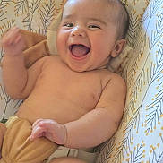 Hezekiah joined the competition — help win amazing prizes! baby, bare_chest, cheerful, child, closeup, cushion, cute, expression, face, happy, indoors, infant, joy, lying_down, patterned_background, person, skin, small_hand, smiling, young