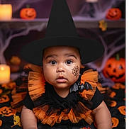 Mía Analia joined the competition — help win amazing prizes! baby, child, halloween, witch_hat, costume, face_paint, pumpkin, jack_o_lantern, blanket, orange, black, bat_brooch, candle, fall_leaves, portrait, cute, holiday, celebration, indoors, toddler