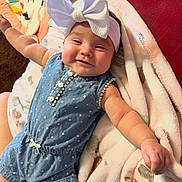 A'Delyna joined the competition — help win amazing prizes! baby, infant, child, smiling, portrait, indoor, lying_down, bow_headband, blue_outfit, polka_dots, denim, blanket, soft_blanket, couch, red_background, toy, colorful, cozy, happy, face