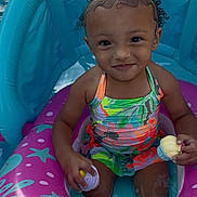 Laylah joined the competition — help win amazing prizes! toddler, child, pool, inflatable_float, water, toy, cupcake_toy, curly_hair, pigtails, colorful_swimsuit, summer, outdoor, playful, smiling, sitting, fun, swimming_pool, baby, cute, portrait
