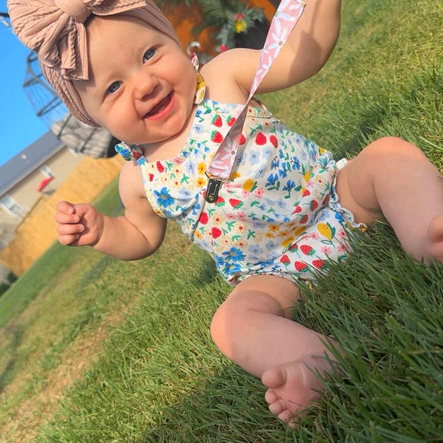 Kensley joined the competition — help win amazing prizes! baby, barefoot, bench, child, cute, fence, floral_outfit, grass, happy, headband, infant, outdoor, pacifier, pink_bow, plant, playful, smiling, summer, sunny, yard