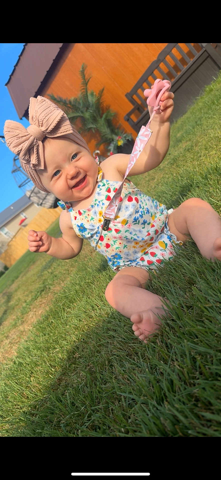Kensley joined the competition — help win amazing prizes! baby, child, grass, outdoor, sunny, headband, pink_bow, pacifier, smiling, floral_outfit, barefoot, yard, bench, fence, plant, happy, summer, cute, infant, playful