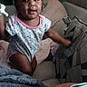baby, blanket, child, couch, face, floral_clothing, happy, home, indoors, infant, living_room, natural_light, pillow, portrait, short_hair, sitting, smiling, sofa, toddler, window