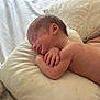 arms, baby, blanket, closeup, cozy, face, head, indoors, infant, naked, newborn, peaceful, person, pillow, resting, skin, sleeping, smile, soft, toddler