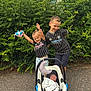 baby, bushes, car_seat, child, cute, family, greenery, happy, newborn, outdoor, pavement, person, playing, plush_toy, sibling, smiling, sportswear, striped_shirt, stroller, toy