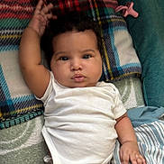 Kahlani Forman is registered to the contest to win money with this photo: baby, child, infant, white_onesie, blanket, cushion, plaid, striped, hand, face, curly_hair, lying_down, indoors, soft_texture, cute, portrait, skin, expression, comfort, resting