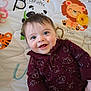 animal_print, baby, baby_clothing, bear_pattern, blue_eyes, child, closeup, cute, giraffe_cartoon, happy, indoor, infant, lion_cartoon, maroon_onesie, panda_cartoon, play_mat, portrait, smiling, tiger_cartoon, yellow_toy