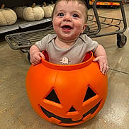Lazarus is registered to the contest to win money with this photo: baby, child, costume, cute, decorative_pumpkins, festive, floor, halloween, happy, holiday, indoor, infant, orange, person, playful, pumpkin_bucket, seasonal, shopping_cart, smiling, store