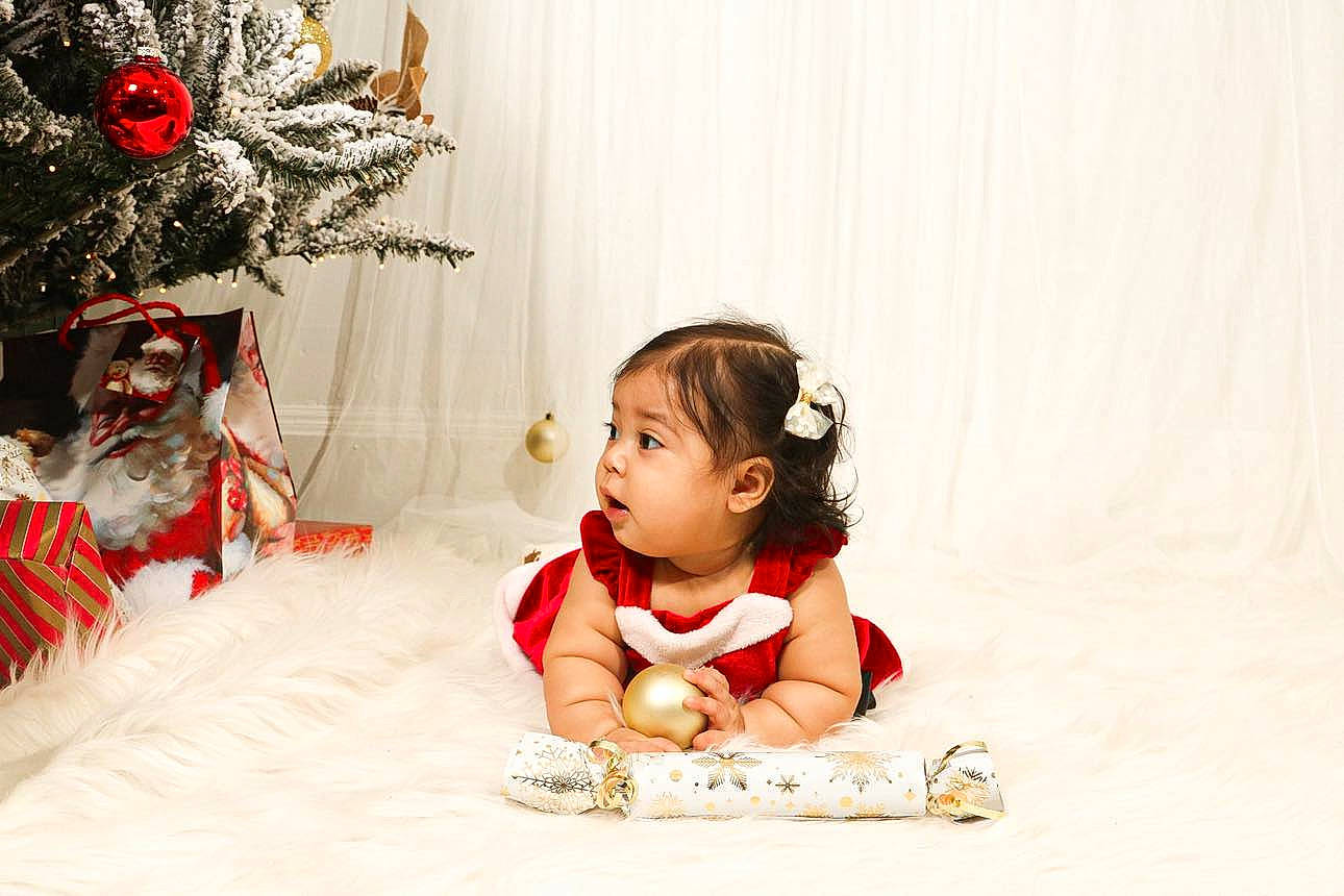 Sofia is registered to the contest to win money with this photo: baby, baby_toddler_clothing, child, christmas_decoration, christmas_ornament, christmas_tree, conifer, event, flooring, fun, happy, head, holiday, holiday_ornament, ornament, person, room, sitting, sleeve, toddler