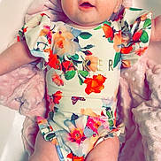 Myla-Rae joined the competition — help win amazing prizes! baby, infant, child, blue_eyes, floral_outfit, pink_blanket, soft_texture, cute, toddler, lying_down, chubby_legs, smiling, portrait, indoors, skin, hair, person, closeup, colorful_clothing, happy