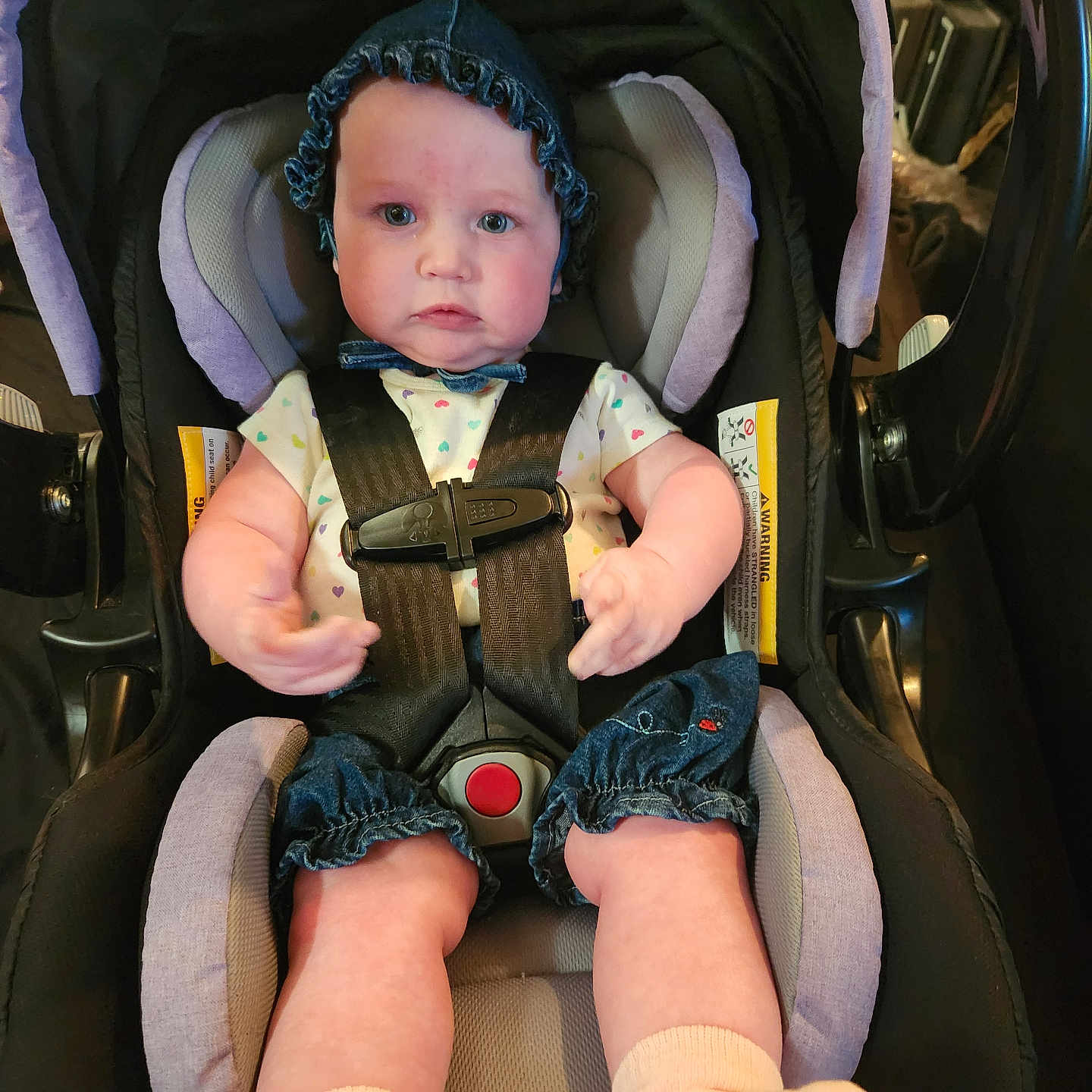 Ava is registered to the contest to win money with this photo: baby, car_seat, child, infant, clothing, bonnet, seatbelt, cute, indoor, person, portrait, legs, hands, socks, fabric, headwear, baby_girl, car_interior, seat, straps