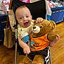 Mason joined the competition — help win amazing prizes! baby, child, teddy_bear, stroller, plush_toy, toy, smiling, happy, indoor, shopping, clothing, flooring, bag, retail, store, seat, wood_floor, person, cute, celebration