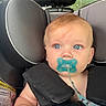baby, infant, child, car_seat, pacifier, blanket, portrait, face, blue_eyes, red_hair, sitting, secured, vehicle, car_interior, headrest, safety_harness, cozy, close_up, indoors, photography