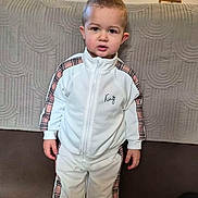 Kaïs a rejoint le concours — aidez-le/la à gagner de superbes lots ! child, eyes, face, floor_tiles, hand, home, indoor, jacket, neutral_expression, person, plaid_pattern, portrait, quilted_couch, shoes, short_hair, sneakers, standing, toddler, tracksuit, young_child