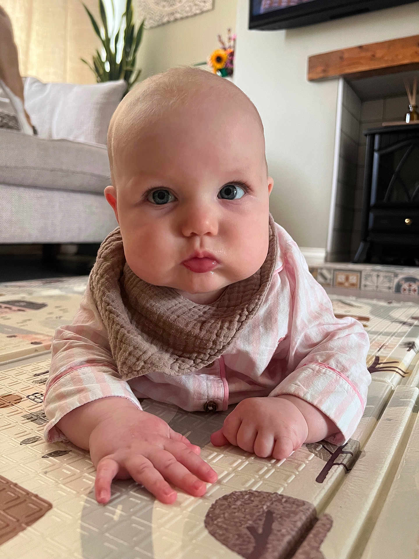 Novie is registered to the contest to win money with this photo: baby, infant, child, face, hands, pajamas, bib, play_mat, indoor, floor, curious, drool, cute, chubby_cheeks, person, portrait, home, soft_lighting, close_up, expression