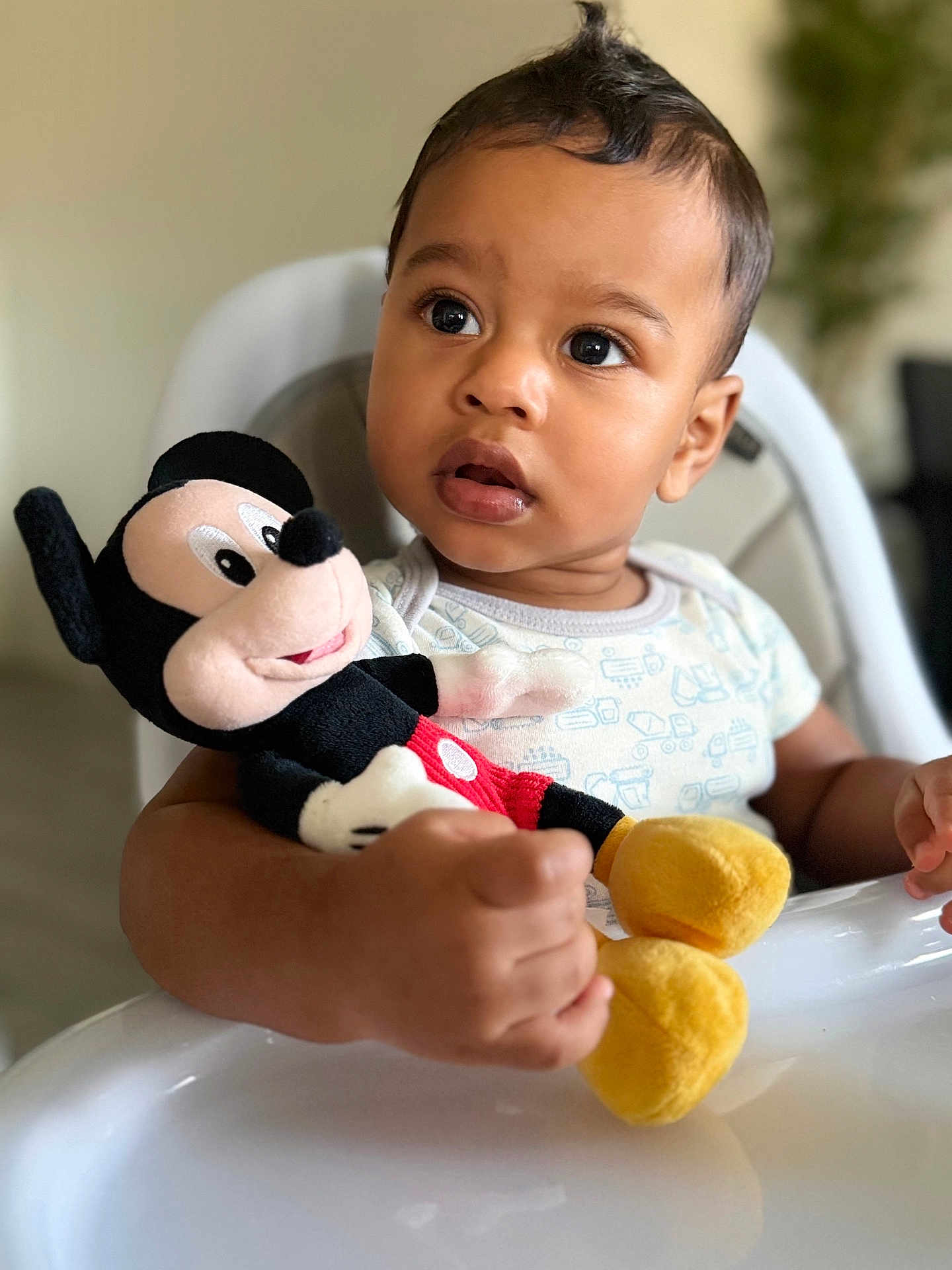 Aharon is registered to the contest to win money with this photo: toddler, child, plush_toy, mickey_mouse, high_chair, indoor, curious, expression, clothing, person, face, hand, toy, seat, baby, closeup, portrait, soft_focus, furniture, cute
