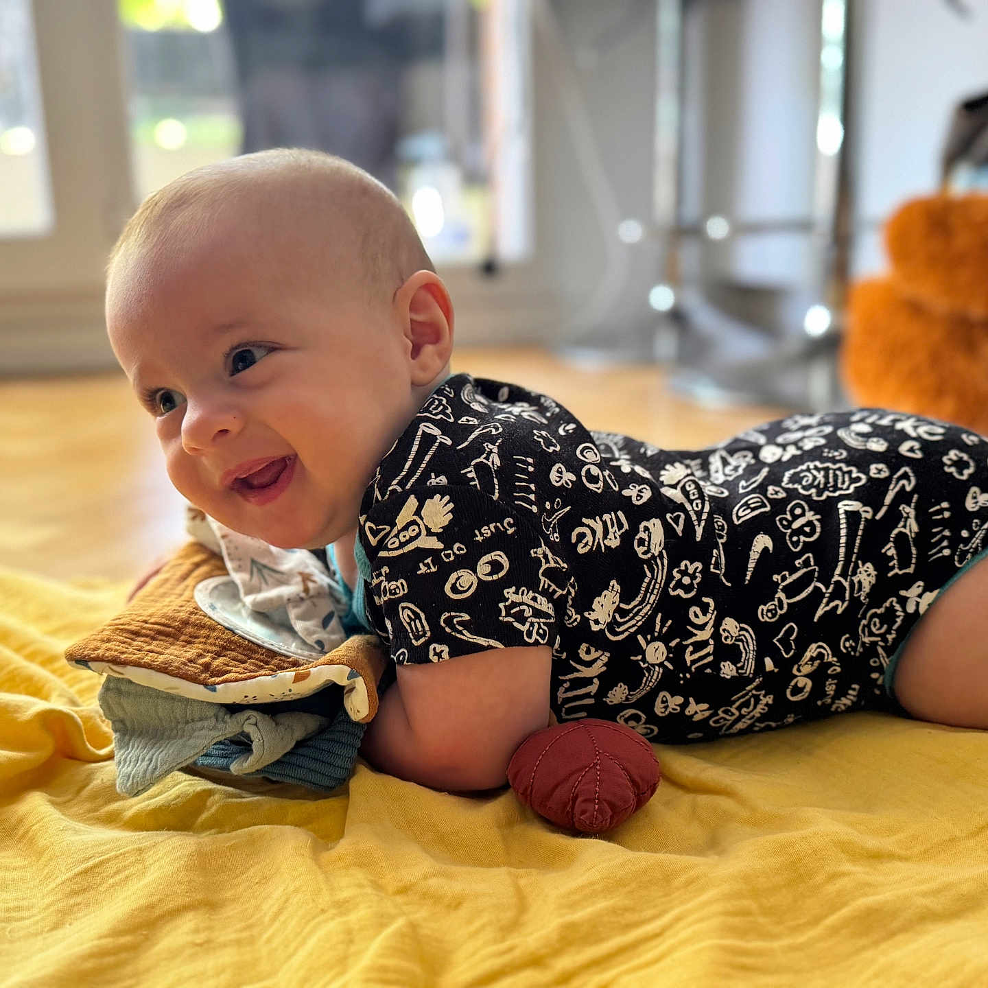 Ilyan a rejoint le concours — aidez-le/la à gagner de superbes lots ! baby, blanket, cheerful, clothing, cushion, cute, fabric, face, floor, happy, head, home, indoors, infant, lying_down, natural_light, portrait, smiling, soft_toy, toddler