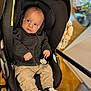 Ilyan a rejoint le concours — aidez-le/la à gagner de superbes lots ! baby, child, infant, car_seat, black_hoodie, beige_pants, white_sneakers, indoor, floor, wood_floor, toy, seatbelt, cute, portrait, clothing, footwear, person, small_hands, expression, looking_away