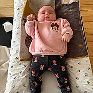 Rose participe au concours pour gagner de l'argent avec cette photo : baby, infant, child, mickey_mouse, minnie_mouse, pink_sweatshirt, patterned_pants, white_socks, changing_pad, wooden_table, towel, floor, indoor, cute, person, clothing, face, expression, lying_down, soft_toys