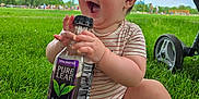Oliver is registered to the contest to win money with this photo: baby, child, grass, outdoor, park, smiling, happy, bottle, drink, pure_leaf, sweet_tea, greenery, tree, sunny, daylight, sitting, infant, barefoot, summer, nature
