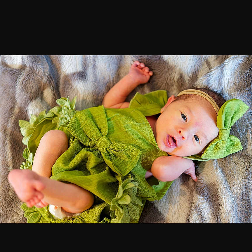 Jade a rejoint le concours — aidez-le/la à gagner de superbes lots ! baby, blanket, bow, child, comfortable, cozy, cute, expression, face, green_dress, happy, headband, indoors, infant, lying_down, newborn, portrait, skin, small_feet, soft_texture