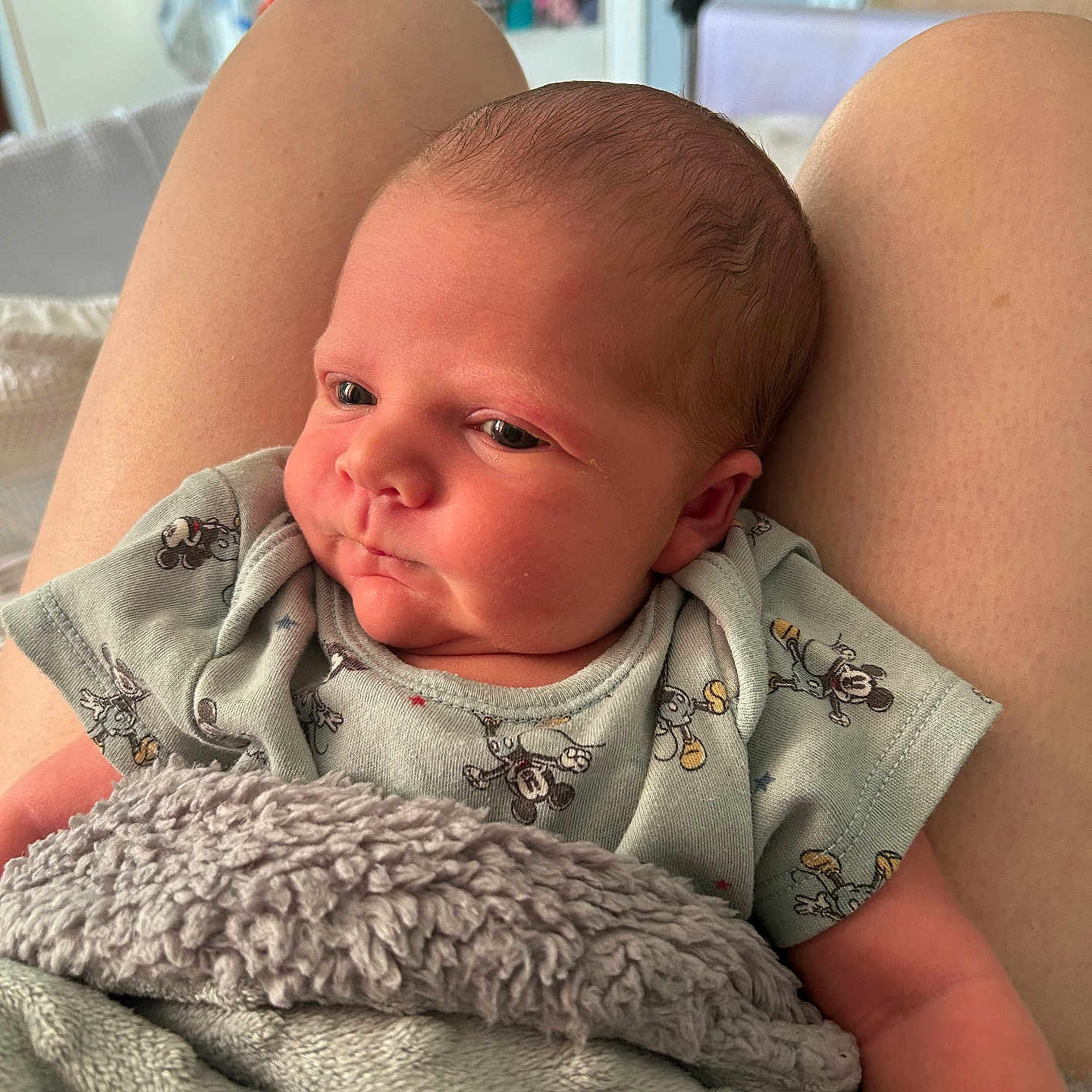 Artie is registered to the contest to win money with this photo: baby, blanket, child, clothing, comfort, cute, face, head, indoors, infant, lap, mickey_mouse, newborn, person, portrait, rest, sitting, skin, soft_texture, young