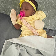 Divinity joined the competition — help win amazing prizes! baby, sleeping, pacifier, yellow_outfit, headband, mittens, blanket, bed, pillow, infant, cute, peaceful, resting, indoor, soft_lighting, child, toddler, cozy, fabric, comfort