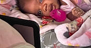 Divinity is registered to the contest to win money with this photo: baby, blanket, pacifier, infant, sleepwear, bed, child, person, face, hand, soft, comfort, cute, indoors, rest, lying_down, warm, cozy, wrapped, pink