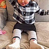 black_skirt, blanket, child, comfort, couch, cozy, cushion, cute, furniture, girl, hair, happy, headband, indoors, plaid_shirt, portrait, red_wall, sitting, smile, socks