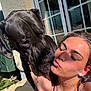 Aston a rejoint le concours — aidez-le/la à gagner de superbes lots ! dog, woman, outdoor, sunlight, affection, kiss, pet, love, face, skin, water_droplets, earrings, necklace, tattoo, hand, window, reflection, shadow, fence, building