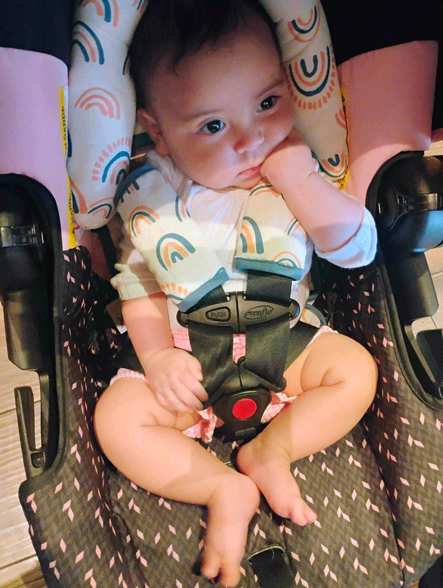 Ava joined the competition — help win amazing prizes! baby, car_seat, child, infant, rainbow_pattern, straps, sitting, pink, white_clothing, barefoot, hand, face, looking_away, indoor, wood_floor, safety_harness, cute, soft_lighting, closeup, person
