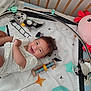 baby, crib, toy, smile, happy, infant, playmat, stuffed_animal, colorful, soft_toys, child, cute, lying_down, indoors, baby_clothes, head, face, expression, joy, background