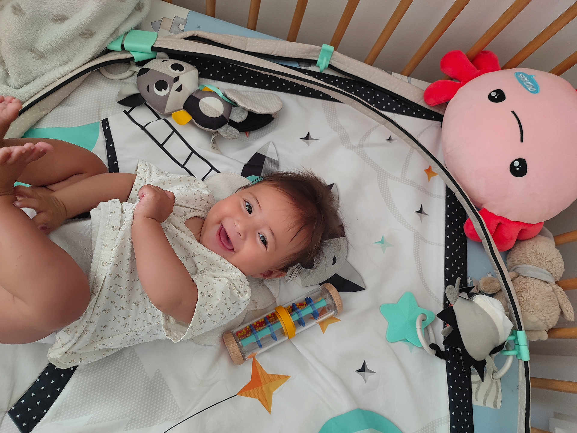 Raphaëlle a rejoint le concours — aidez-le/la à gagner de superbes lots ! baby, crib, toy, smile, happy, infant, playmat, stuffed_animal, colorful, soft_toys, child, cute, lying_down, indoors, baby_clothes, head, face, expression, joy, background