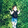 Brayden is registered to the contest to win money with this photo: child, grass, outdoor, sunlight, greenery, casual_clothing, shorts, sneakers, relaxation, nature, summer, playful, boy, bare_arms, daylight, reclining, field, happy, carefree, portrait
