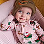 baby, infant, child, beanie, hat, blue_eyes, smile, onesie, santa_print, reindeer_pattern, pink_chair, pajamas, portrait, cute, holiday_theme, looking_up, hand_on_head, indoor, soft_lighting, cozy
