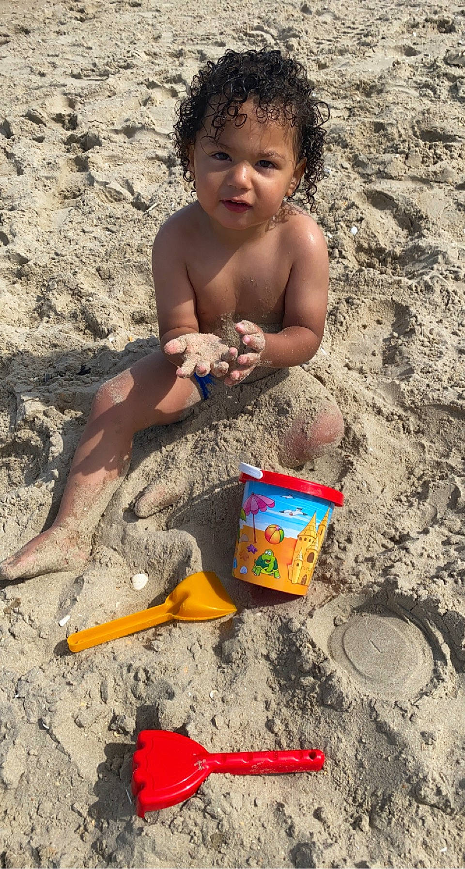 Santino participe au concours pour gagner de l'argent avec cette photo : barechested, barefoot, beach, bucket, child, foot, fun, garden_tool, happy, human_leg, leisure, people_in_nature, person, recreation, sand, sitting, snapshot, soil, thigh, toddler