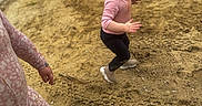 Bria is registered to the contest to win money with this photo: background, black_leggings, casual, child, crocs, curly_hair, expression, footwear, grass, green_leash, leash, motion, nature, outdoor, person, pink_clothing, playful, sandy_ground, toddler, vehicle