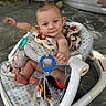 baby, infant, child, baby_rocker, toy, colorful, patterned, barefoot, blue_eyes, curly_hair, outdoor, floor, blanket, plush_toy, seat, expression, cute, person, smiling, playful