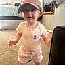 baby, bed, camo, cap, carpet, casual, child, curious, curtain, furniture, home, indoor, person, shirt, shorts, smile, standing, toddler, window, young_child