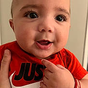 Bradley joined the competition — help win amazing prizes! baby, close_up, face, hand, orange_shirt, smile, pointing, person, child, cute, portrait, indoor, skin, eyes, expression, clothing, adult_hand, wristband, happy, infant
