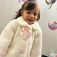 Lauren is registered to the contest to win money with this photo: toddler, child, smiling, coat, pink_bow, hairclip, elephant_wall_decal, moon_wall_decal, lamp, nursery, baby_monitor, bottle, table, indoor, cute, happy, person, portrait, clothing, furniture