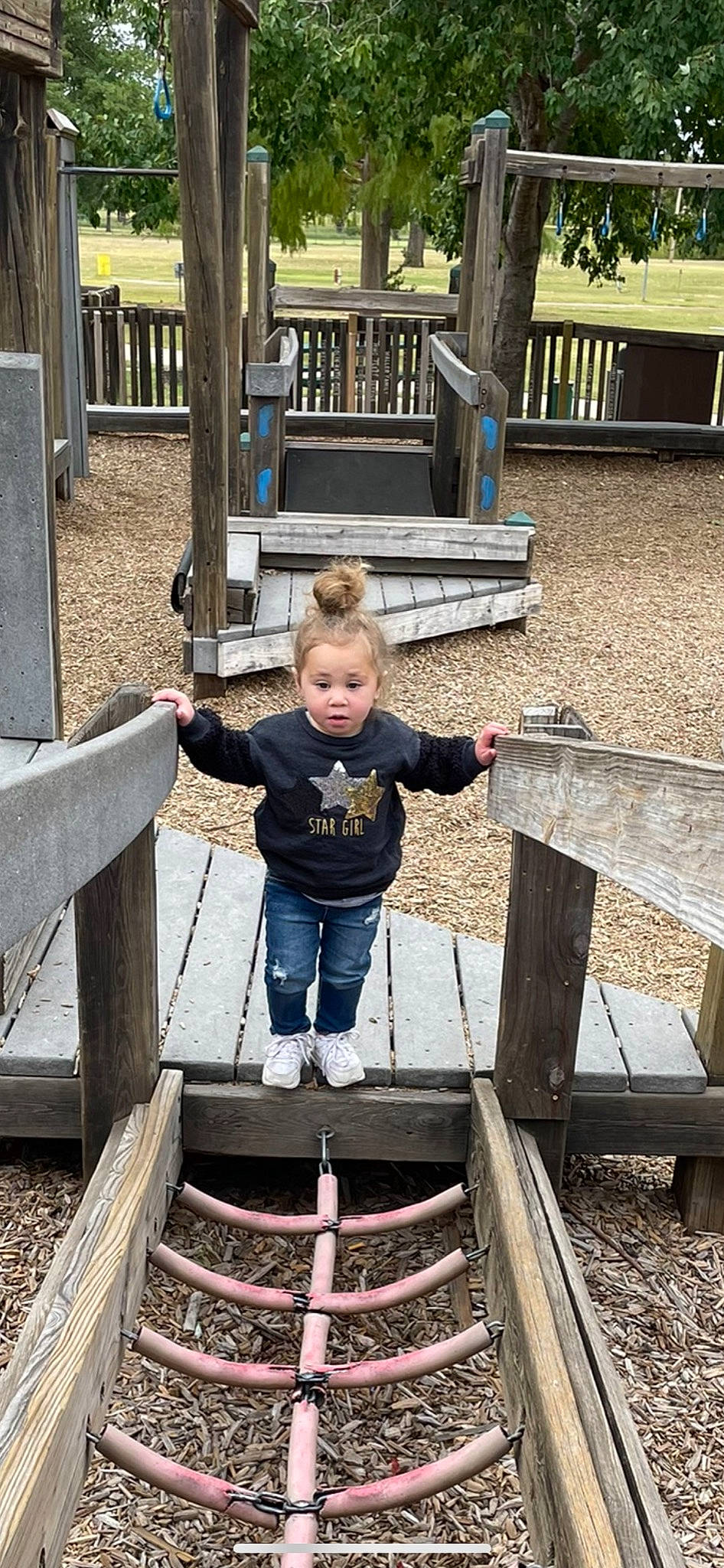 Gia is registered to the contest to win money with this photo: baby, bridge, child, city, denim, fun, grass, handrail, leisure, person, recreation, sitting, soil, t_shirt, toddler, tree, vacation, wood