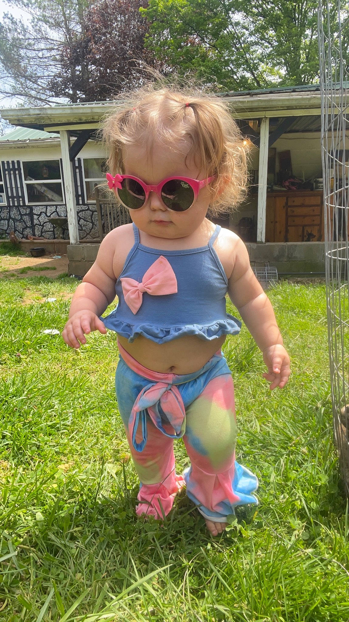 Kimber is registered to the contest to win money with this photo: baby_toddler_clothing, child, electric_blue, eyewear, fun, glasses, goggles, grass, human_leg, leisure, pattern, person, personal_protective_equipment, plant, shorts, sunglasses, t_shirt, thigh, toddler, tree
